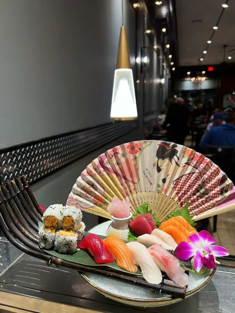 A table with sushi and an oriental fan.