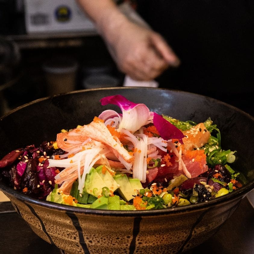 A bowl of salad with dressing being prepared.
